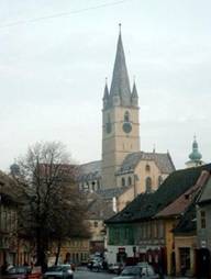 La cathdrale vanglique vue de la ville basse. La placette  l'avant-plan est la Piata Coroana. Plus au loin,  gauche, entre les branchages de l'arbre, on distingue le bulbe de la tour du Conseil,  droite, celui de l'glise catholique.